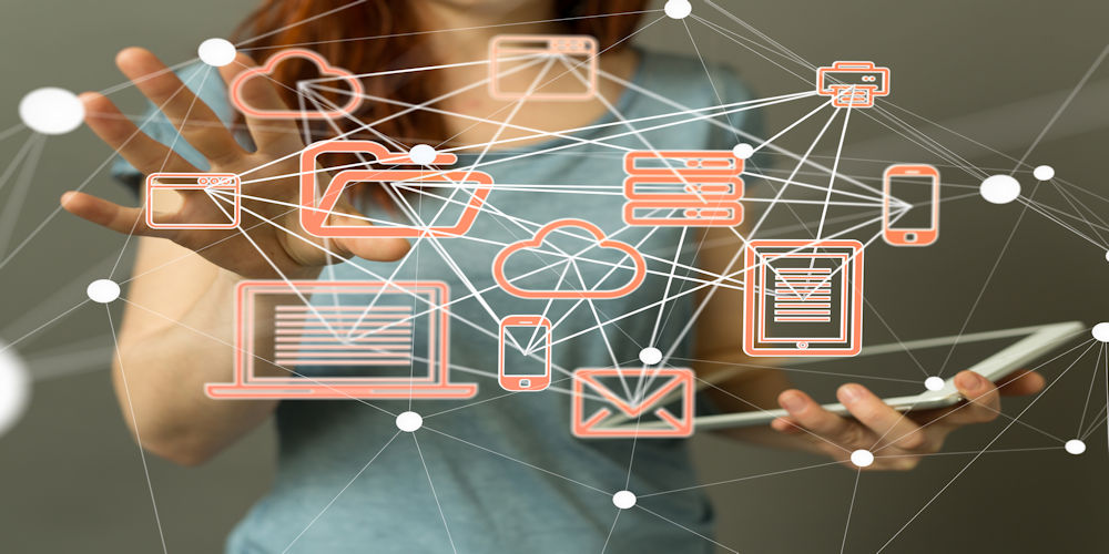 Person holding a tablet with floating orange network icons (cloud, email, laptop, phone) to show digital connectivity and cloud computing.
